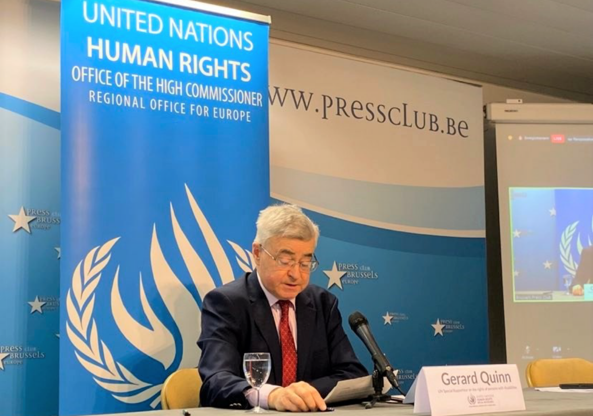 Gerard Quinn looking at a paper and speaking in the mic infront of UN Human RIghts Backdrop.