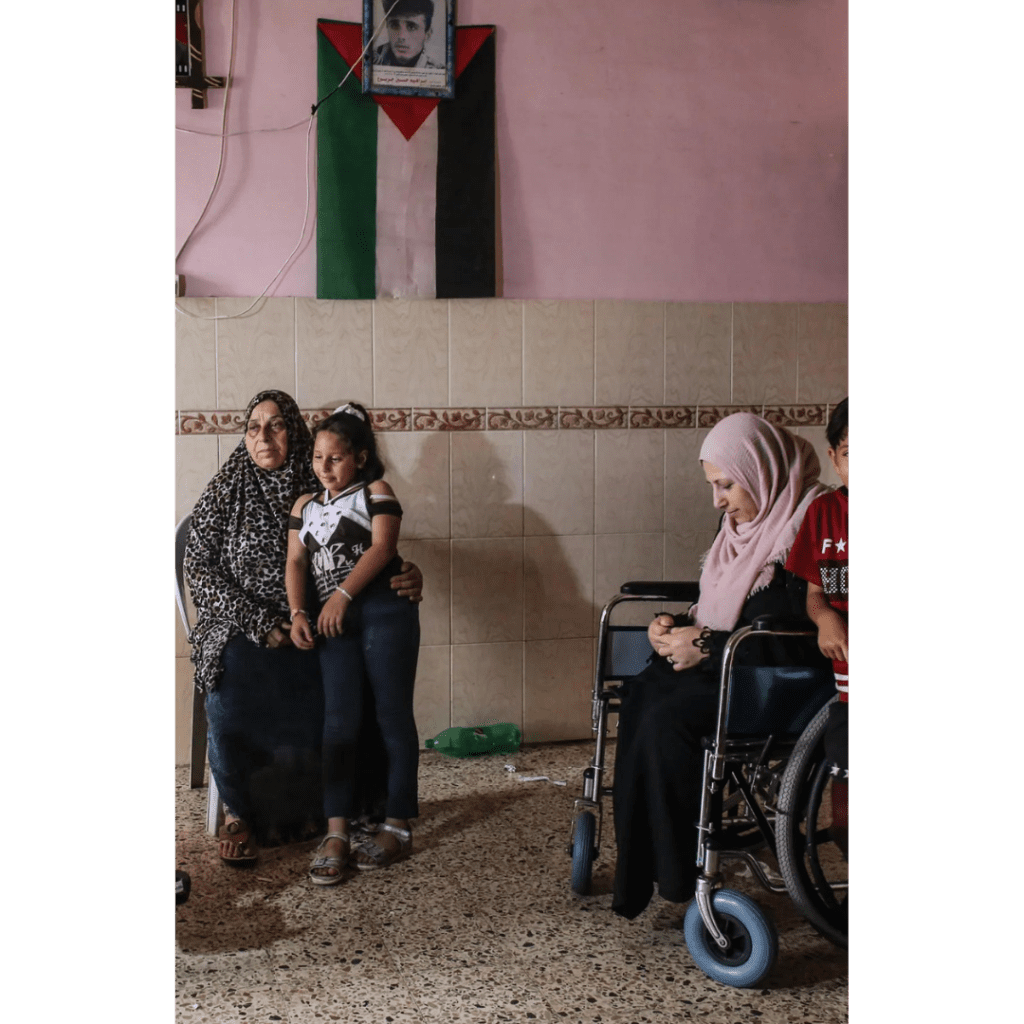 The picture shows two women, one sitting on a chair and the other sitting on a wheelchair. The picture shows the deterioration of the situation of women in Gaza after the war.
