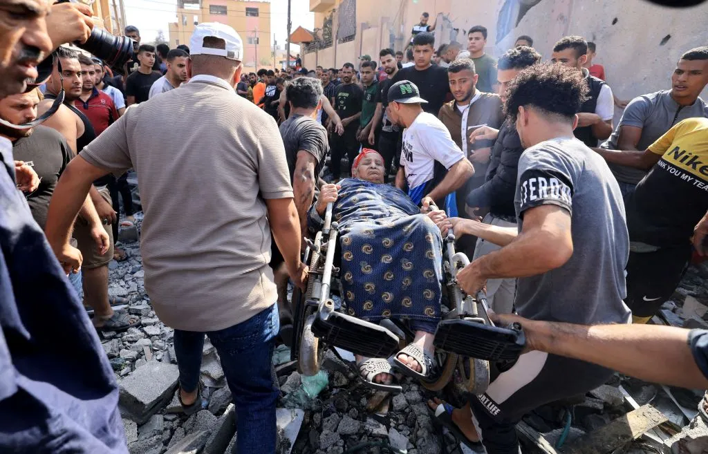 Relief workers rescue an elderly woman in a wheelchair. After an Israeli air strike on Gaza
